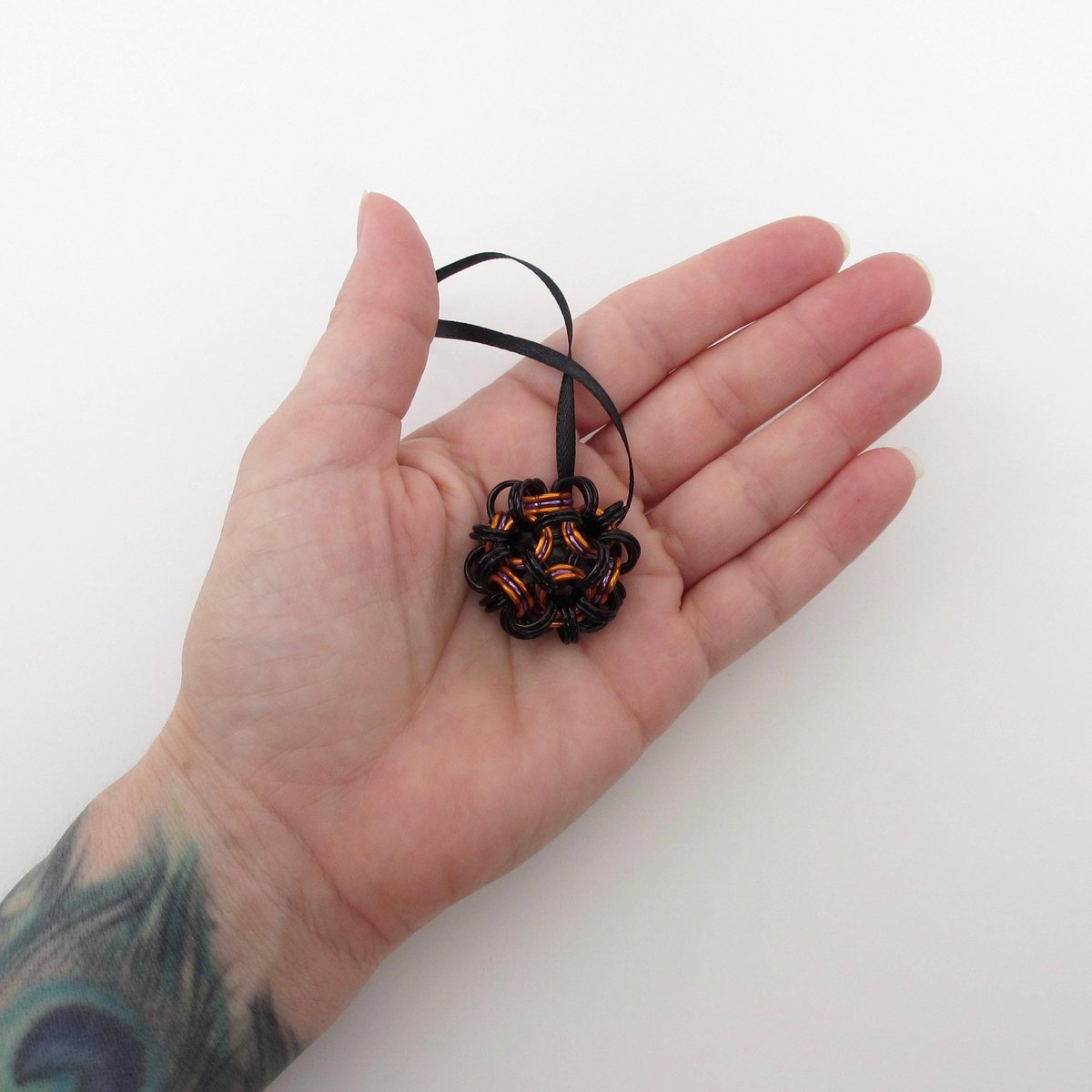 Chainmail Halloween ornament in black and orange with purple accents, handmade dodecahedron ball