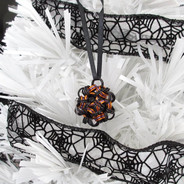 Chainmail Halloween ornament in black and orange with purple accents, handmade dodecahedron ball