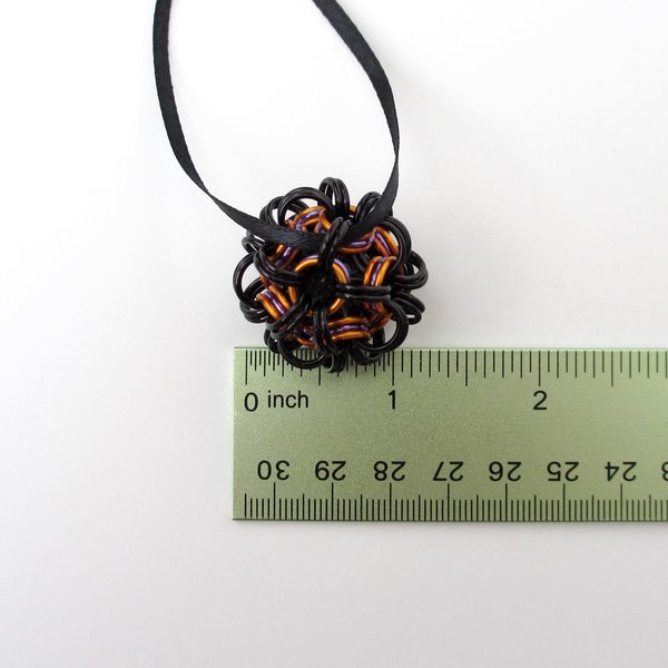 Chainmail Halloween ornament in black and orange with purple accents, handmade dodecahedron ball