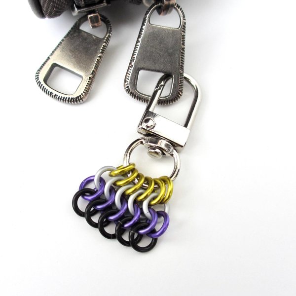 A nonbinary pride flag chainmail zipper pull shown attached to a zipper on a white background.